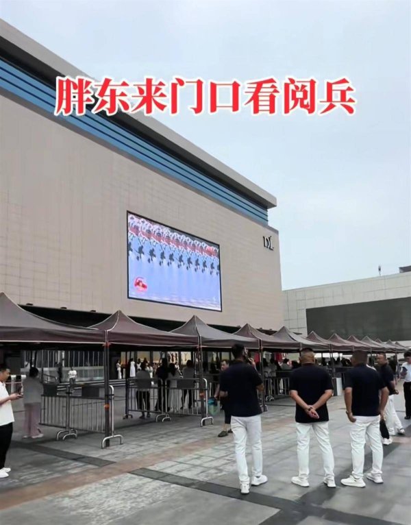 天通盈 胖东来大屏幕直播阅兵，市民雨中驻足观看，工作人员拉来遮阳棚避雨，客服回应